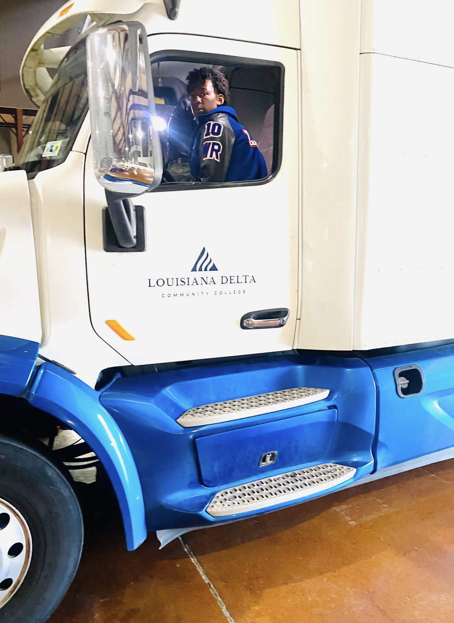 A teen boy sitting in an 18-wheeler.
